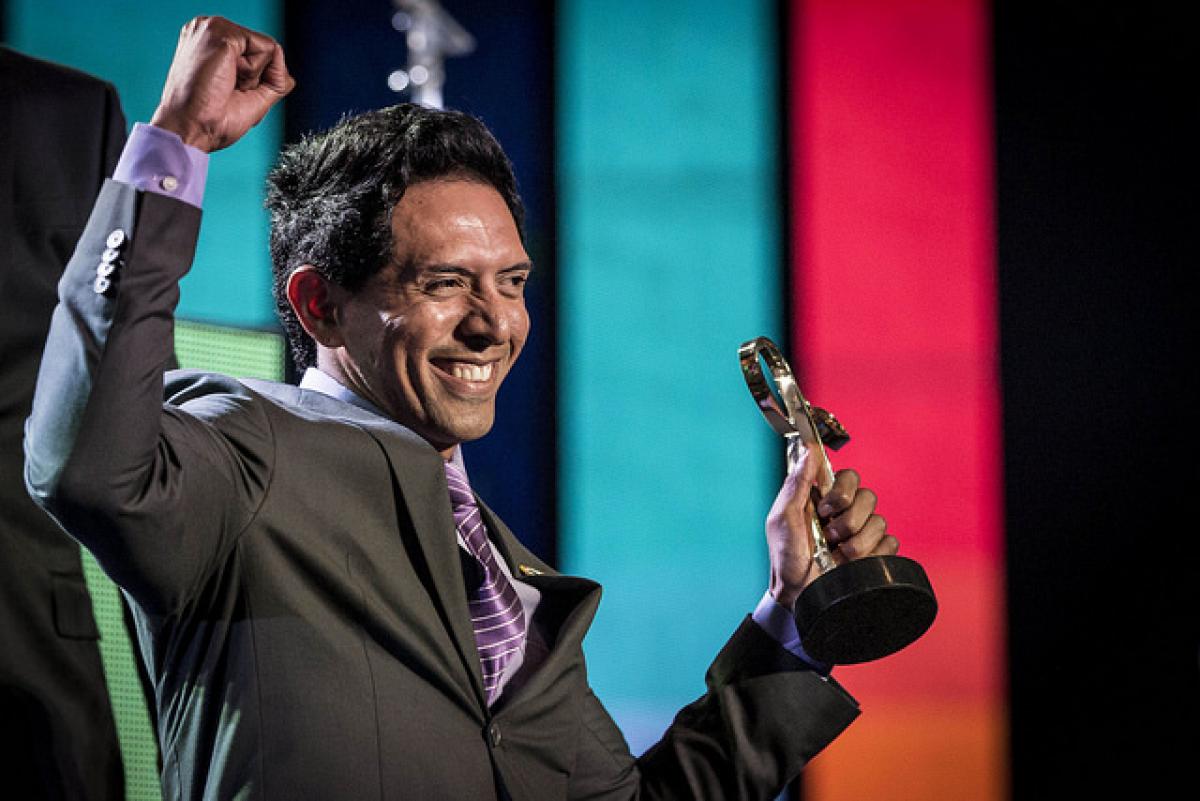 Upper bory of smiling man, holding up a trophy