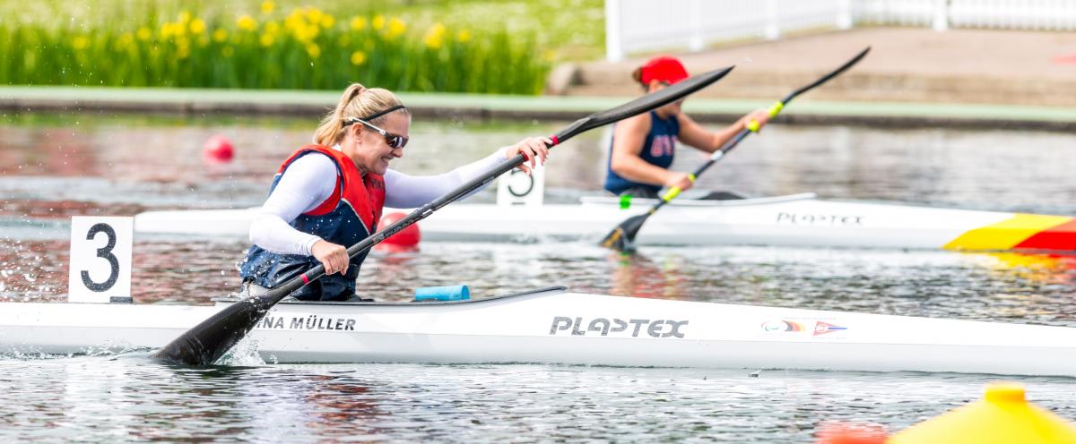 Edina Muller a photo showing the top half of a lady in a canoe wearing a white top, life jacket and sunglasses