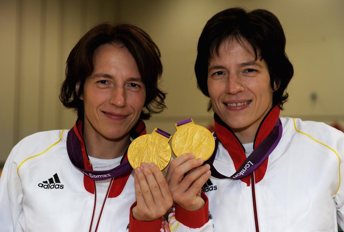 A shot of the upper half of two women holding two Paralympic gold medals