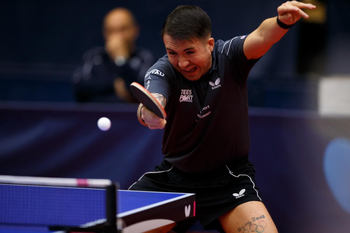 A man wearing a navy shirt playing table tennis