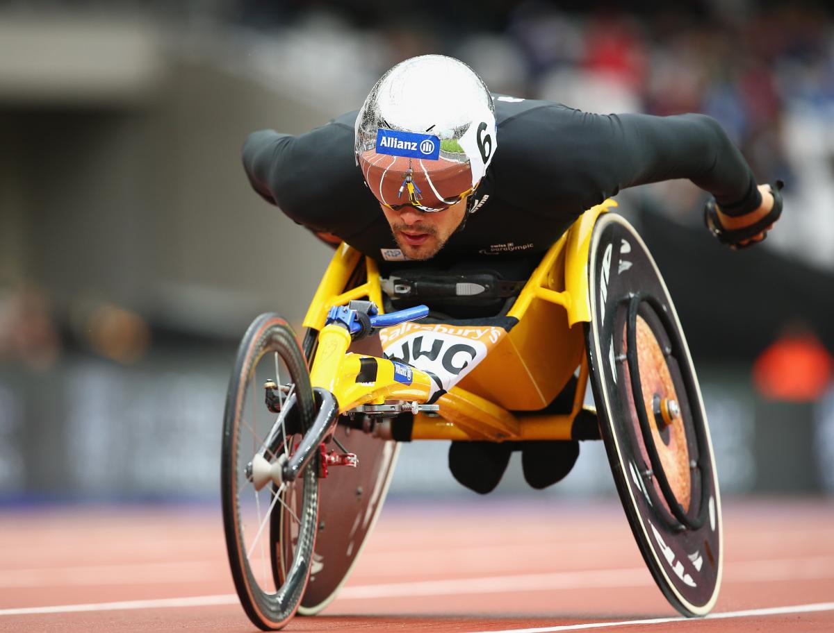 a male wearing black and a helmet racing in a wheelchair