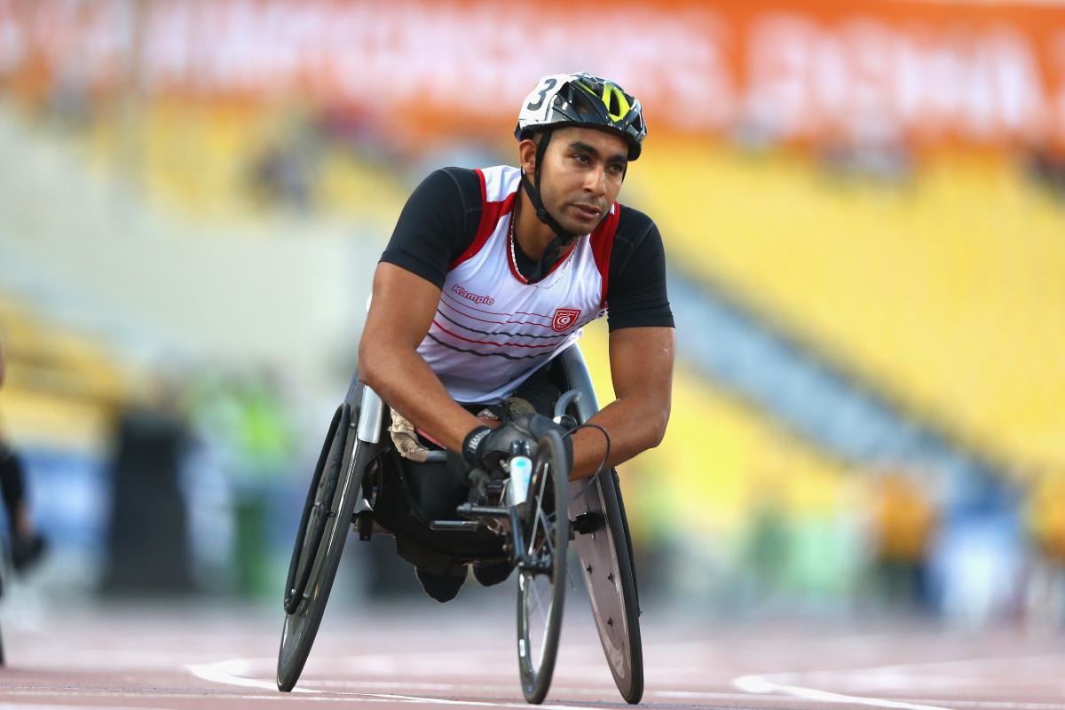 a male from Tunisia wearing a helmet and racing in a wheelchair