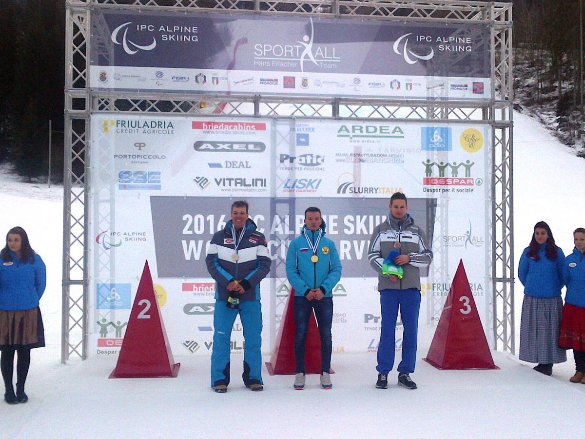 Podium with three men smiling.