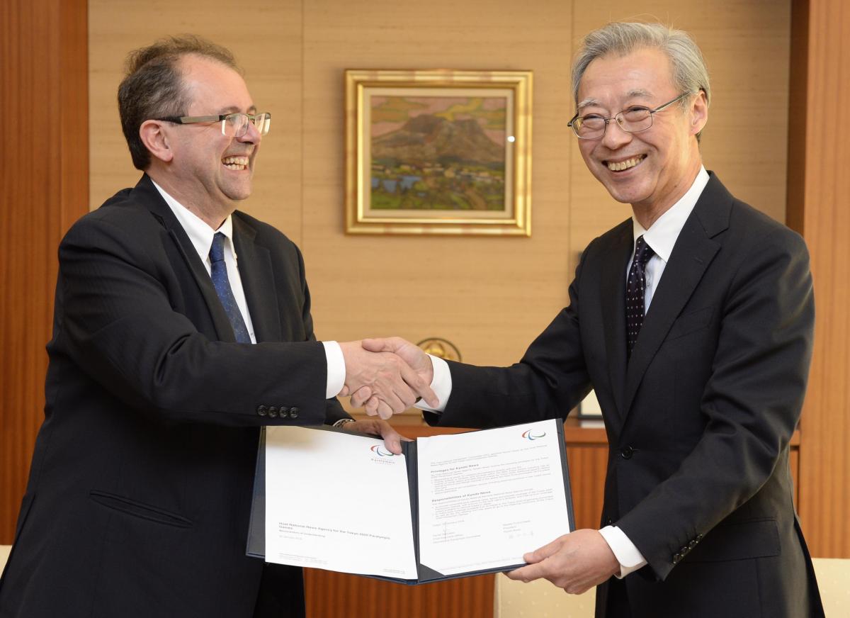 Two men shaking hands, holding a document