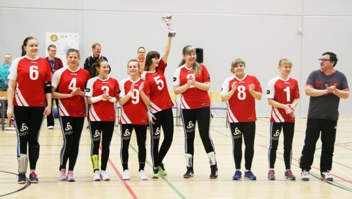 Group of women in red jerseys, showing a trophy, smiling