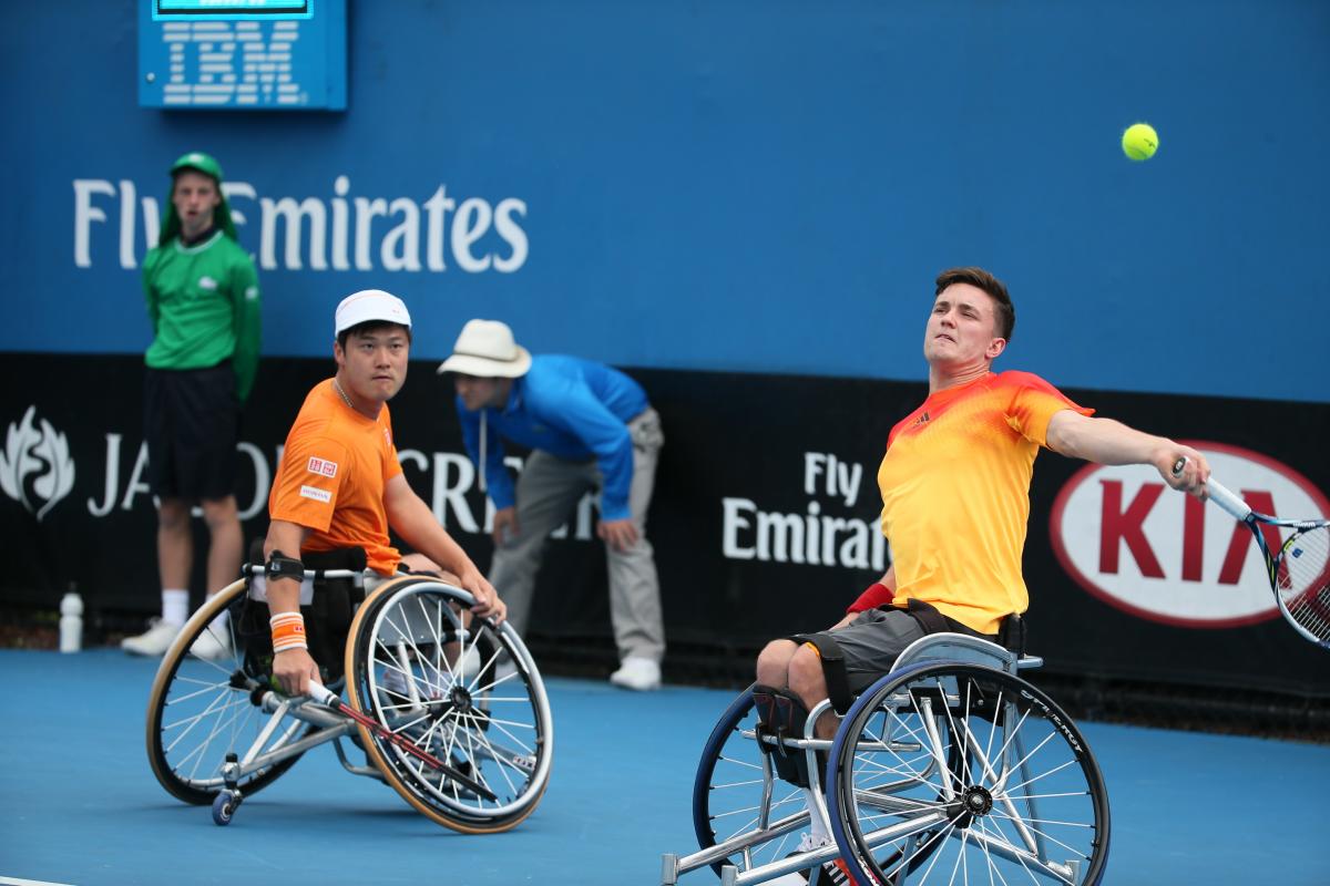 Two men in wheelchairs playing tennis. 