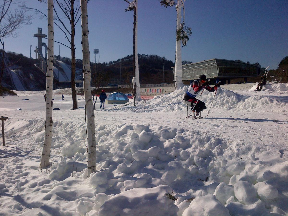 View on a slope with sit skier passing