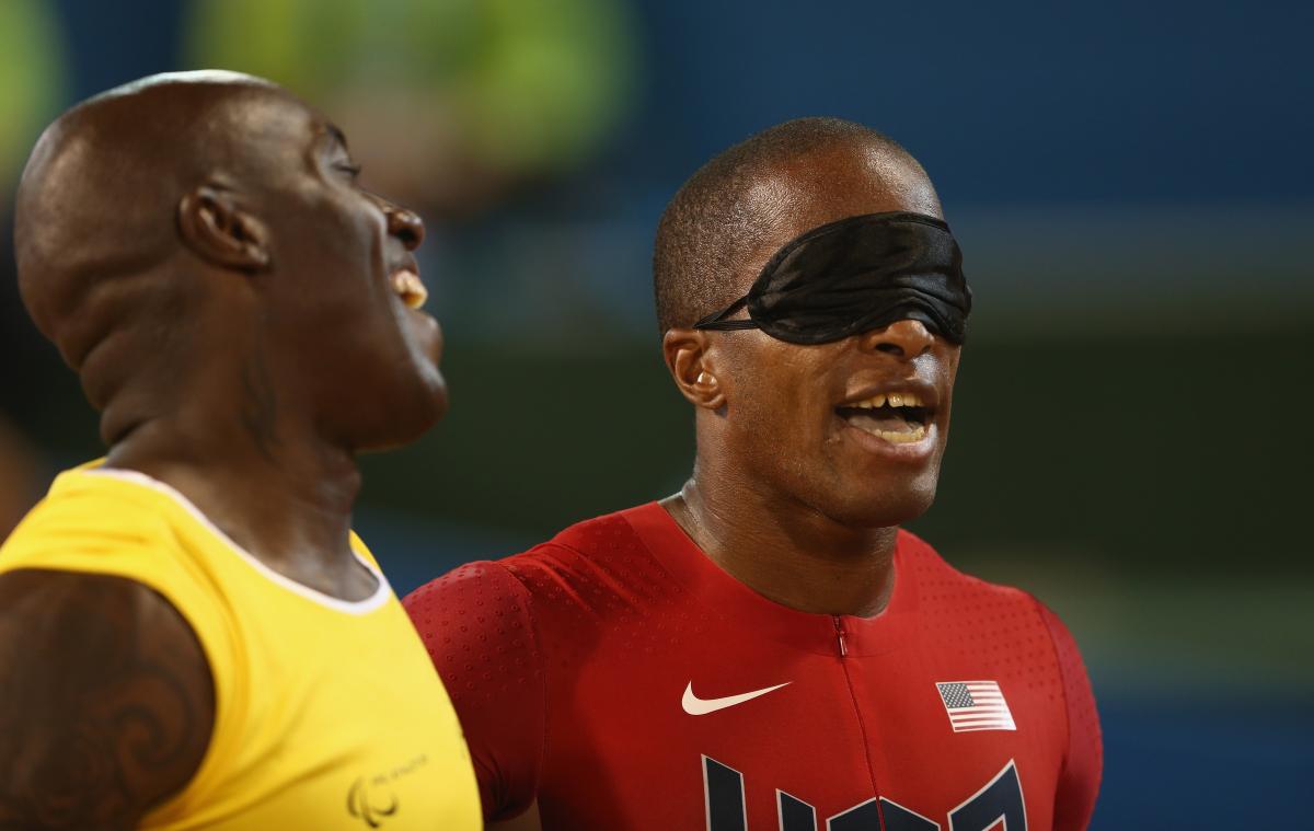 Two men, one blindfolded, laughing