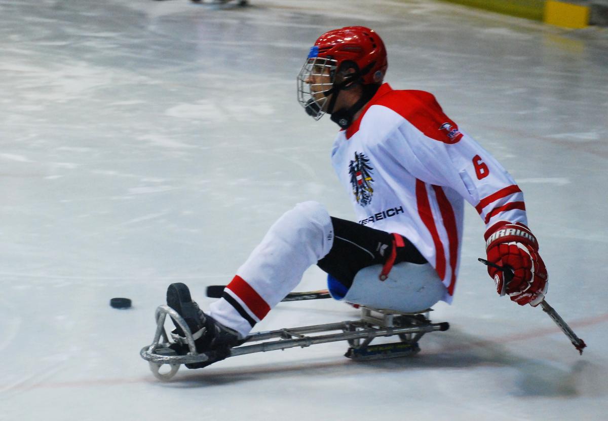 Ice sledge hockey player in red and white jersey on the ice