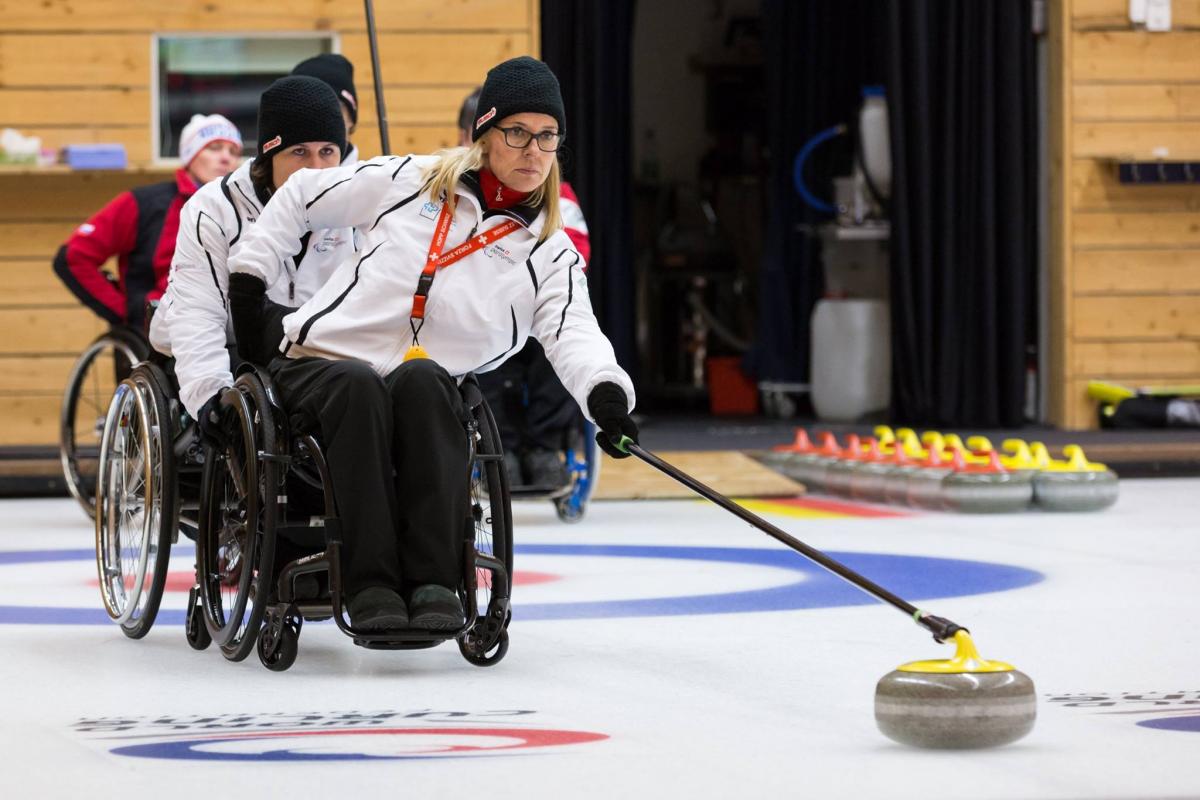 Wheelchair curler on the ice with team in the background