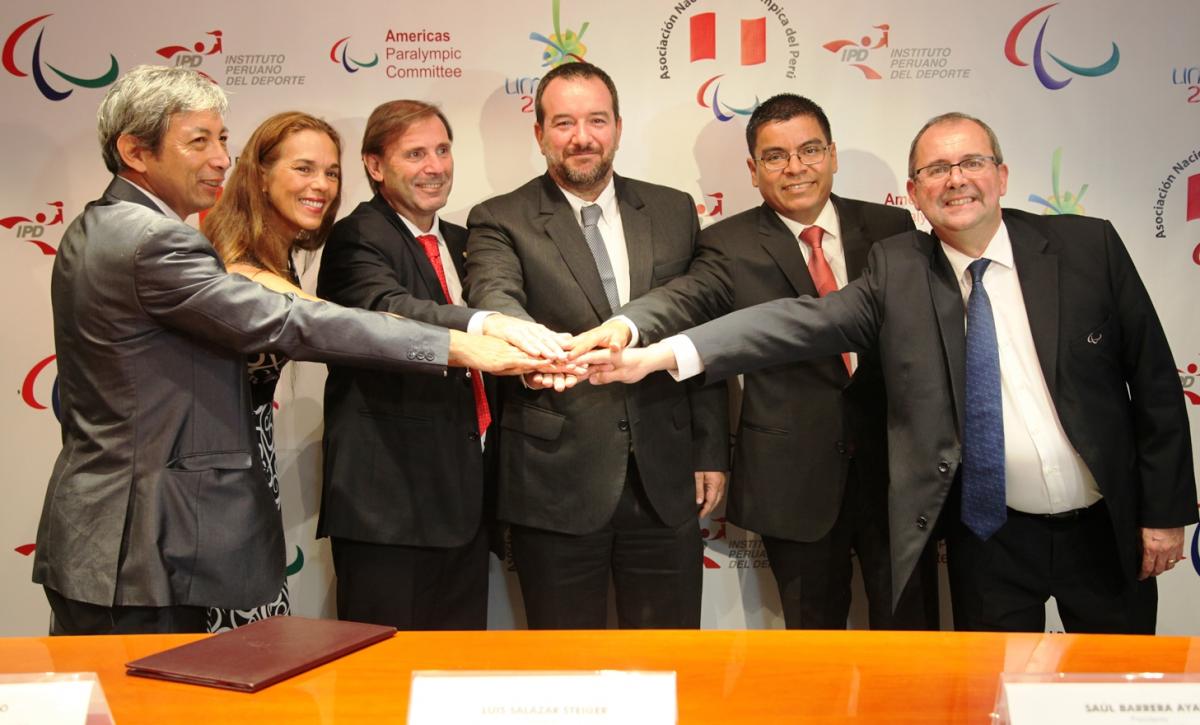 Five men and one women all put their hands together and smile to the camera