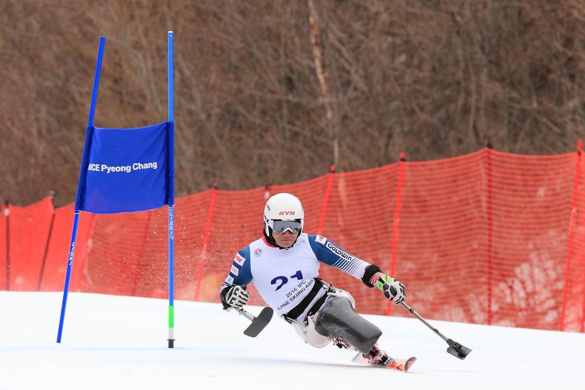 Man in a sit ski passing a gate