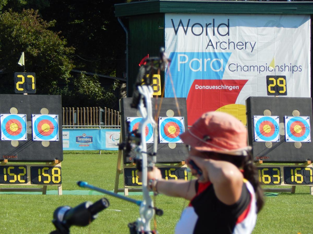 Shot from the back, woman doing archery 