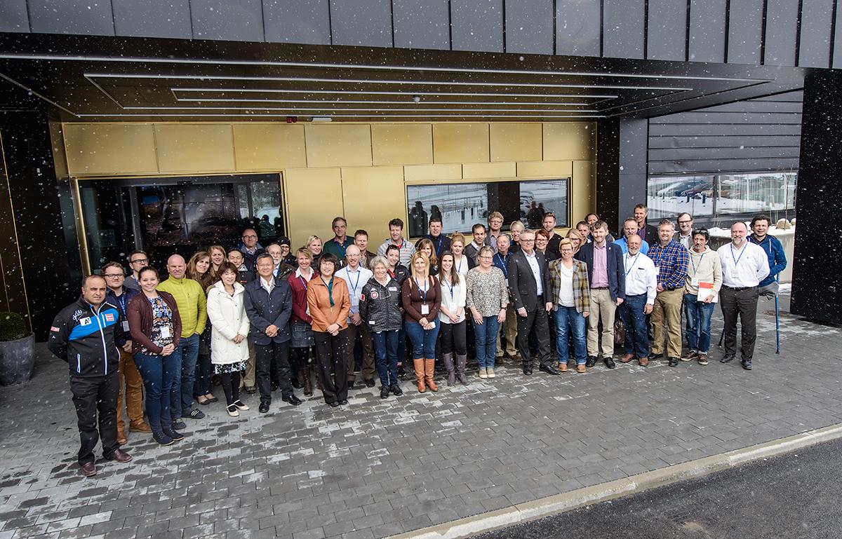 Group shot of 34 people outside a building. It's snowing