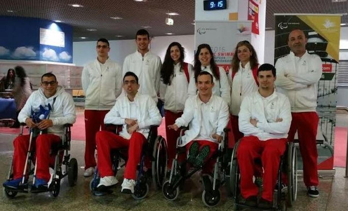 Group shot of athletes standing and in wheelchairs at an airport.