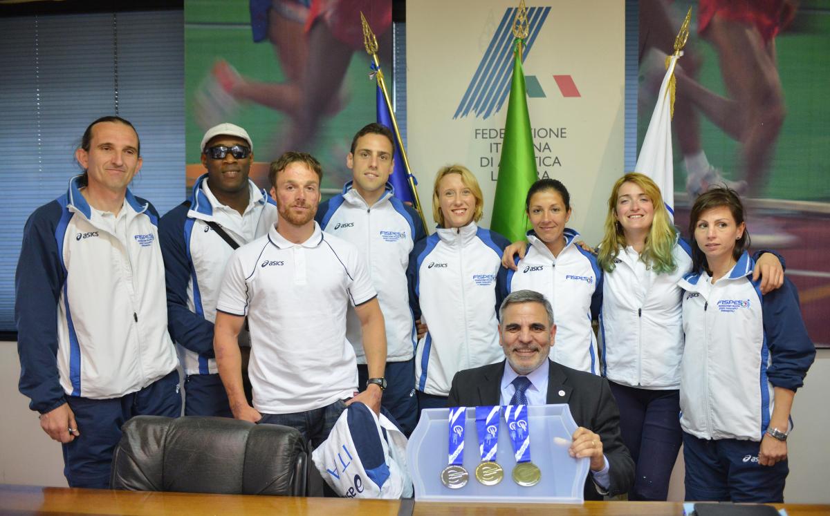 Group of athletes together with an older man showing medals