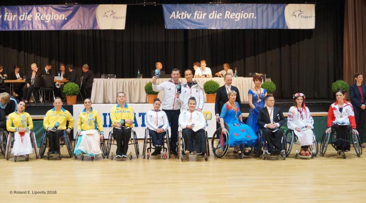 Group picture of people standing and in wheelchairs, showing medals