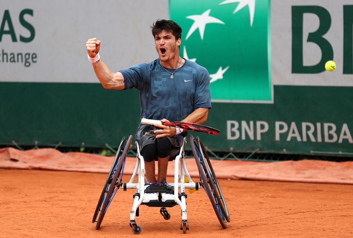Man in wheelchair on tennis court, celebrating