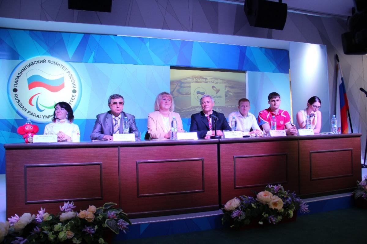 Seven members of the Russian Paralympic Comittee sitting at a desk at a press conference. 