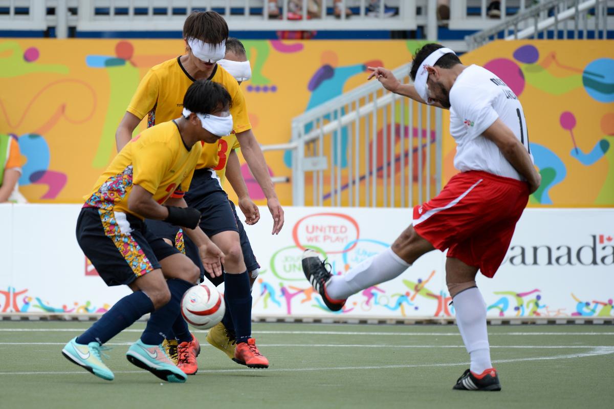 Three blind athletes playing football on a field at the Parapan American Games