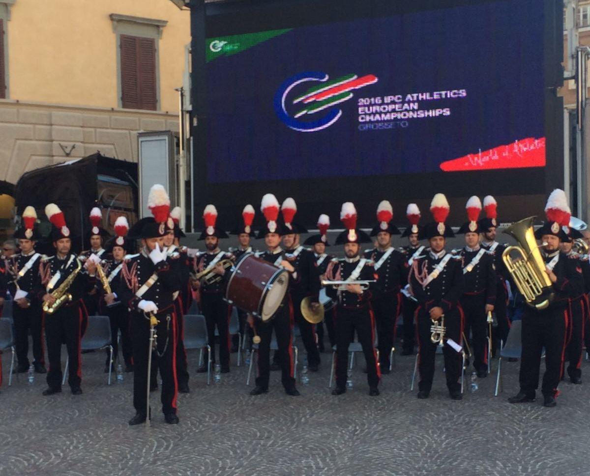 Music band of uniformed men in front of a TV board