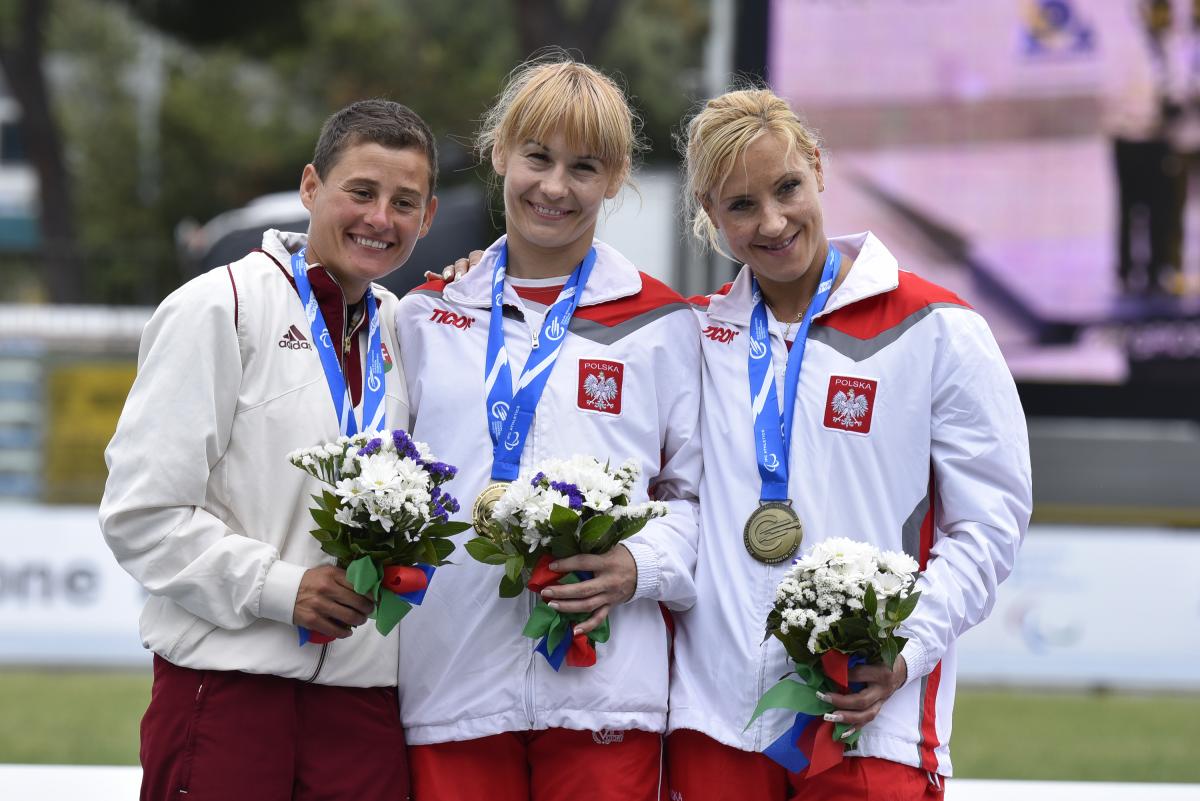 Podium with 3 women holding flowers