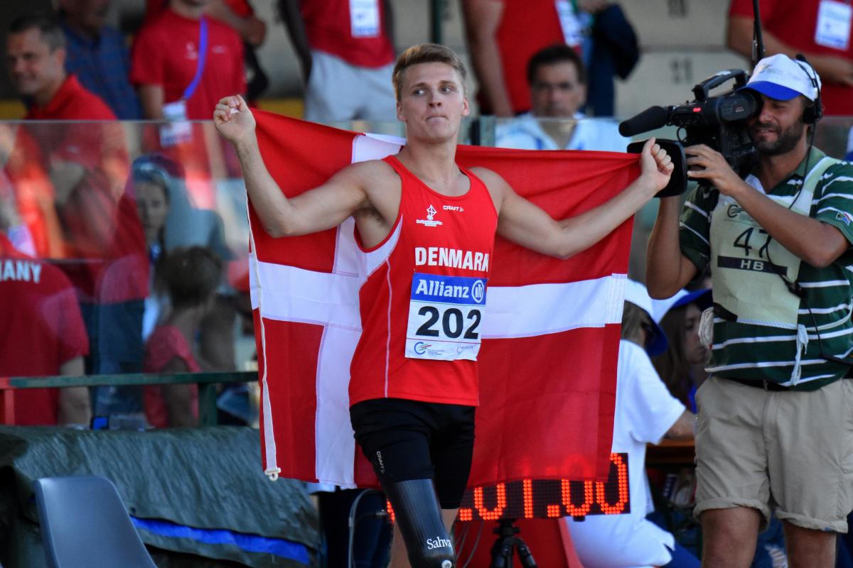 Man in red jersey celebrating with a Danish flag