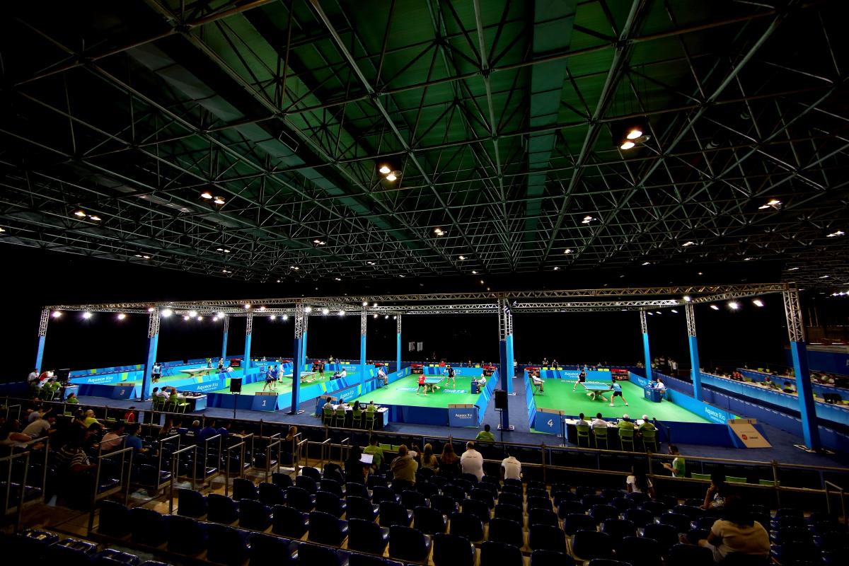 A look inside a venue where table tennis will be contested. On the court are four tennis tables set up.
