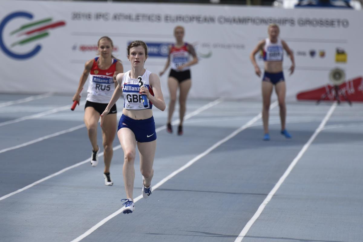Two women running on a blue track