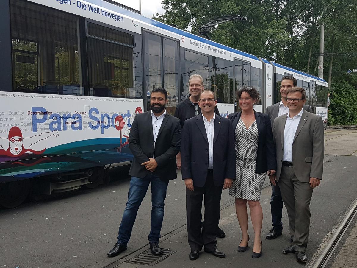 IPC tram Bonn Five people standing in front of a tram in IPC design