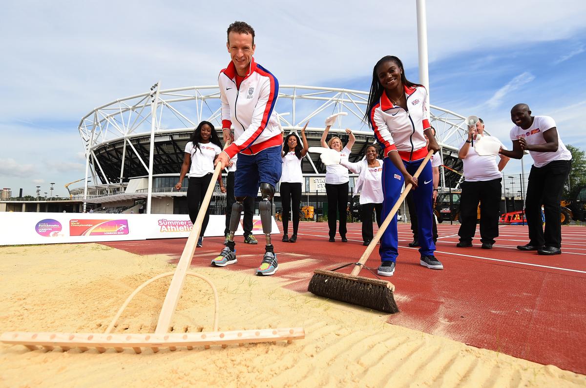 Two athletes cleaning the sand pit