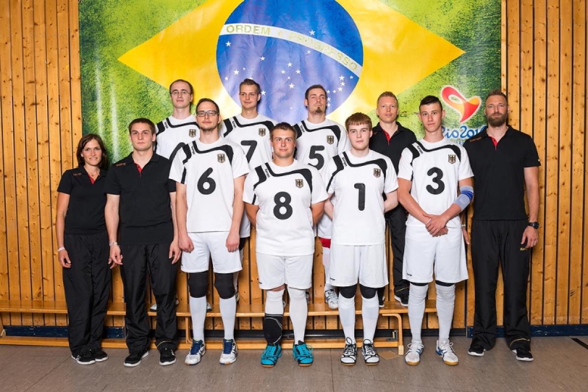 The German goalball team stands in front of a Brazilian flag.