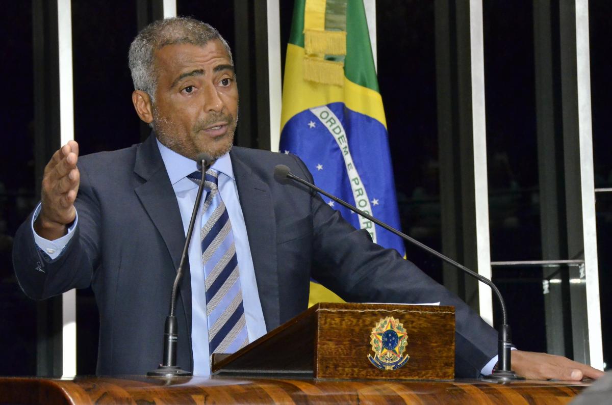 Portrait photo of a man in front of a Brazilian flag