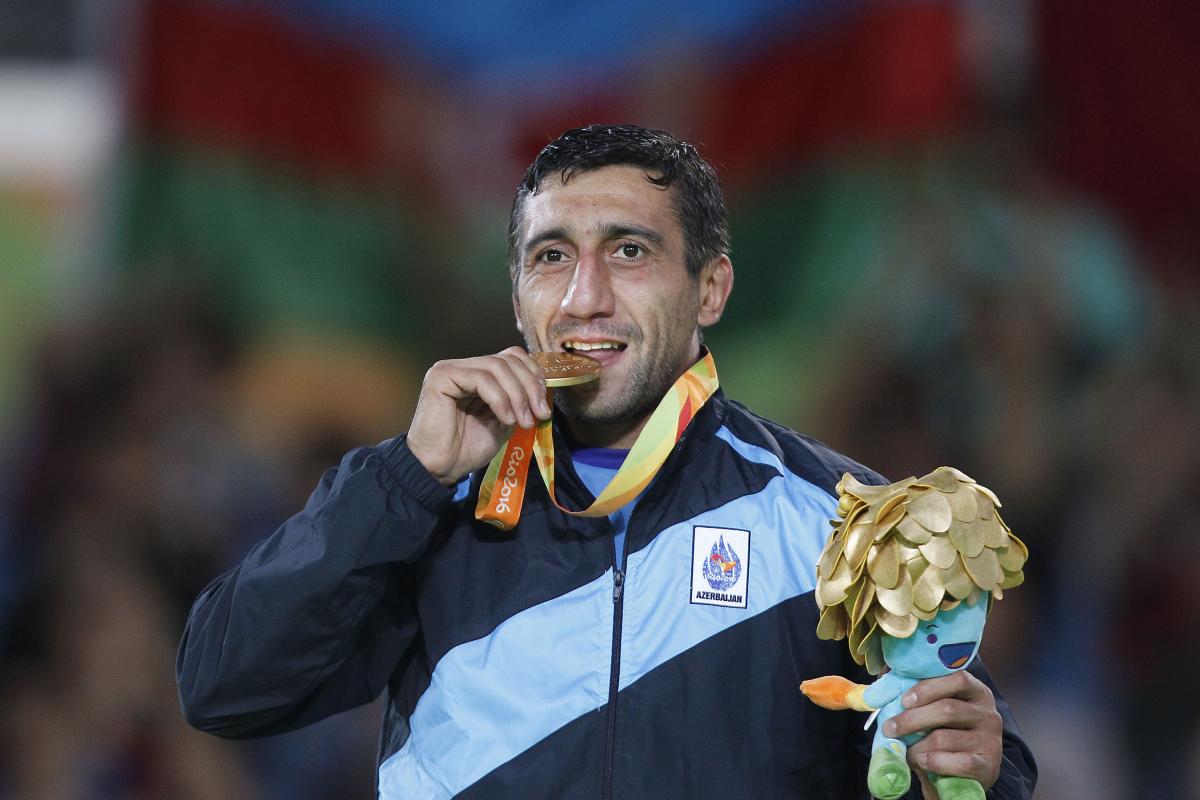 a man bites his medal in celebration