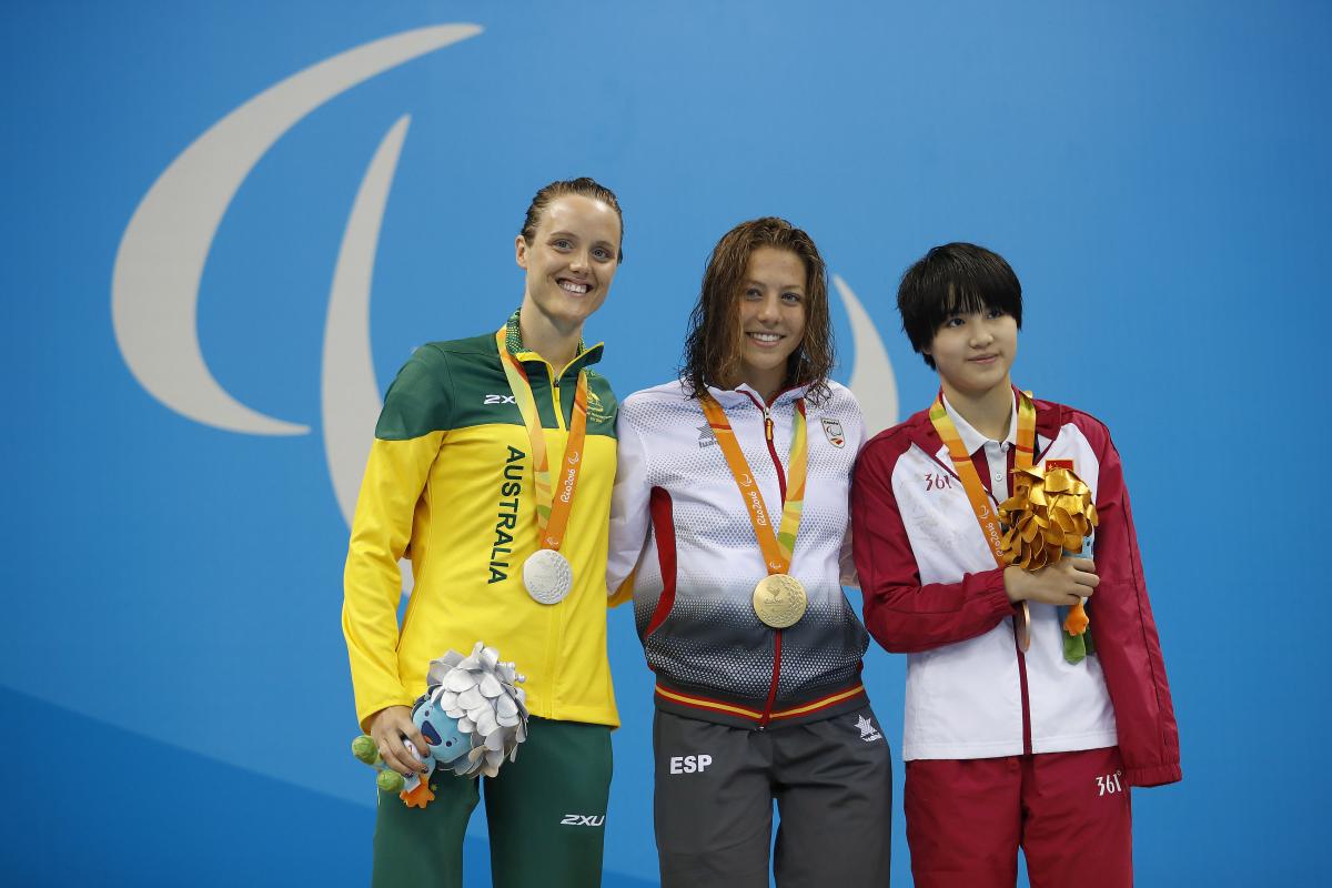 Three women with medals on the podium