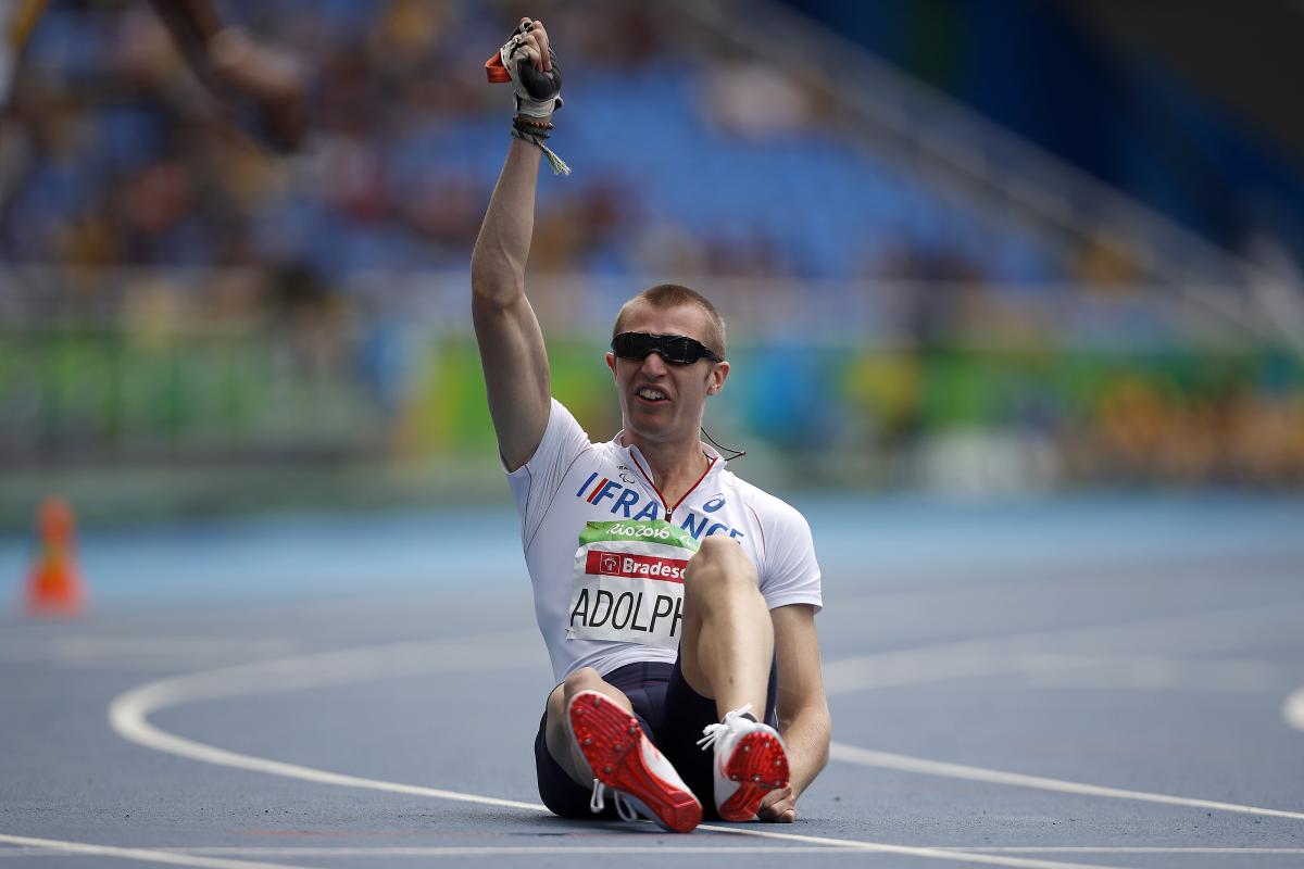 Man sitting on a track raising one arm