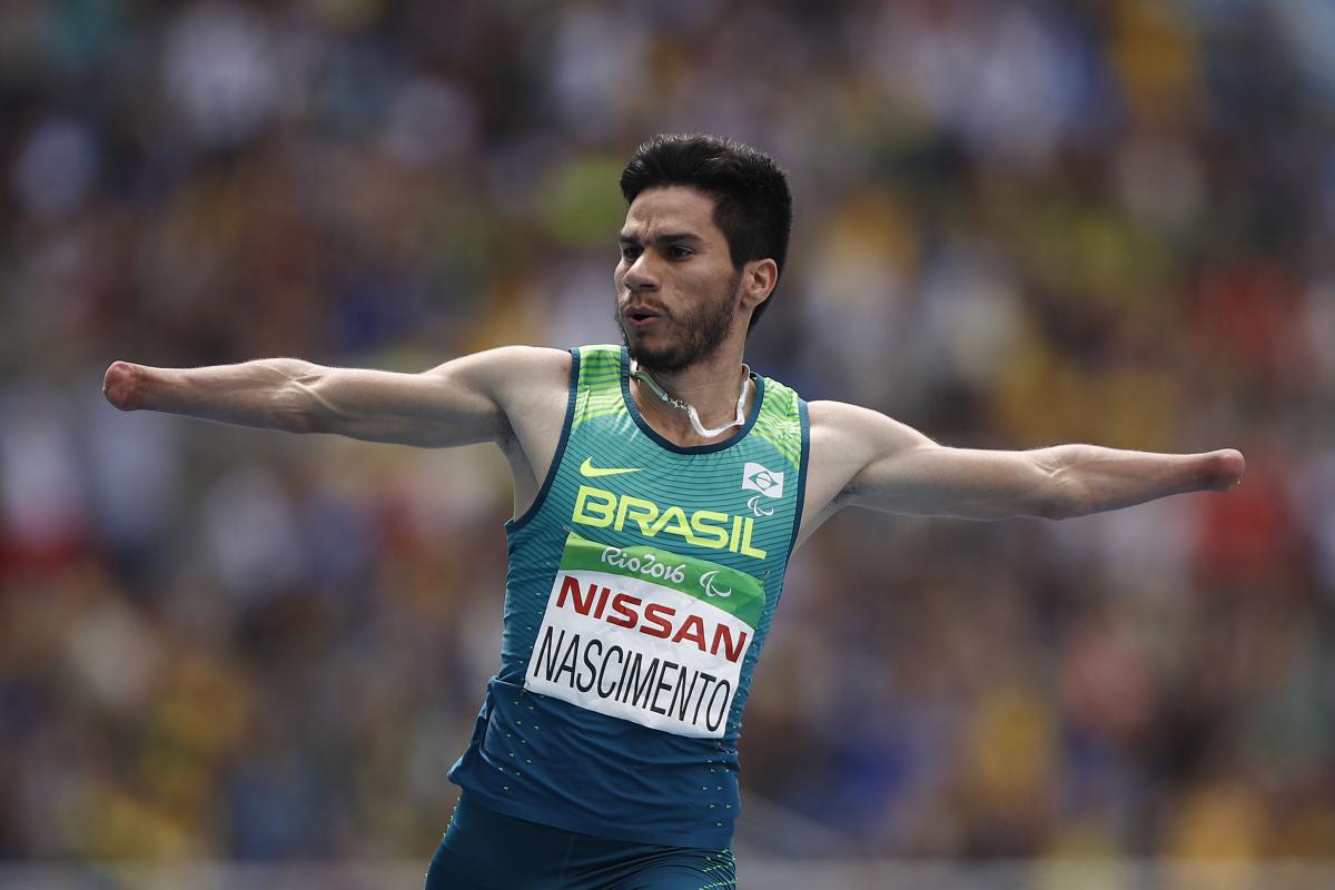 a male Para sprinter celebrates crossing the line