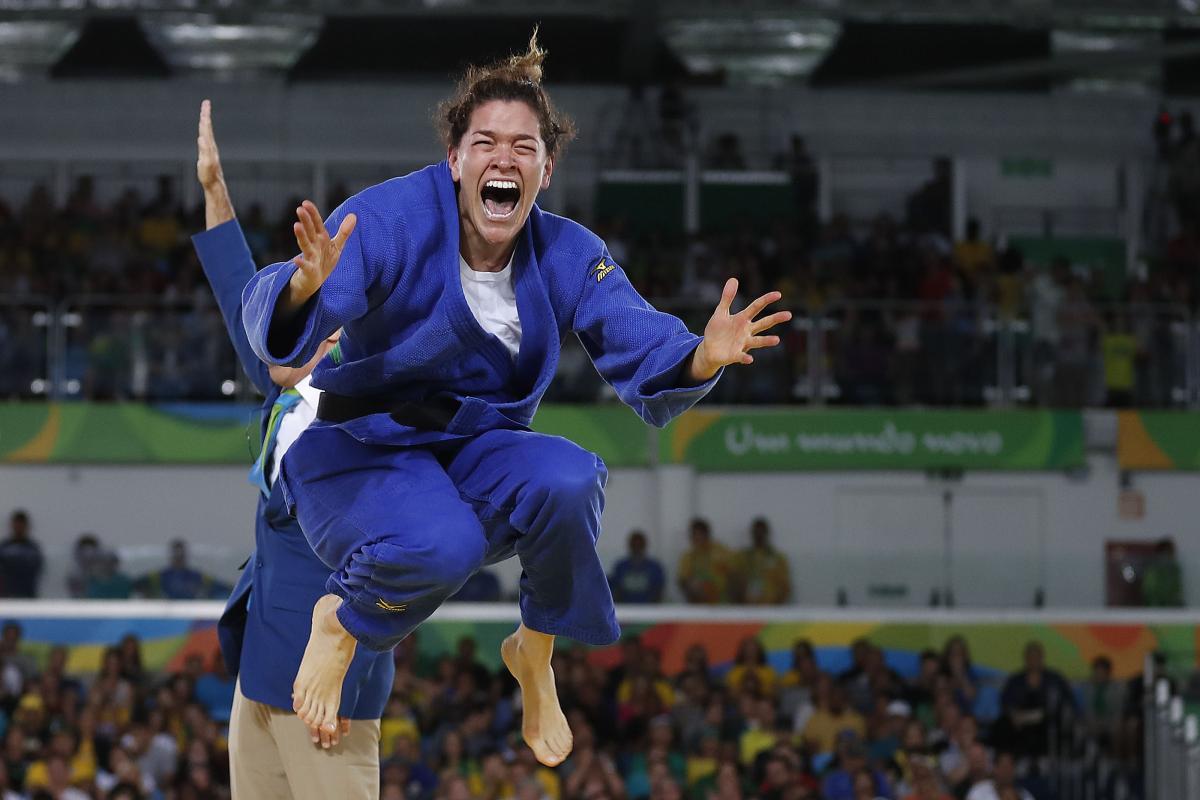a female Para judoka jumps in the air in celebration