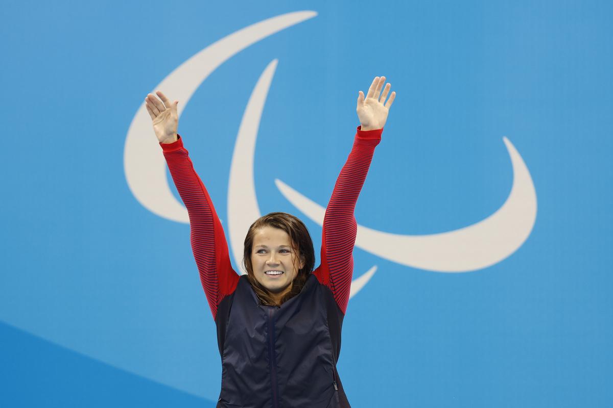 Upper body of a woman, raising her arms in the air