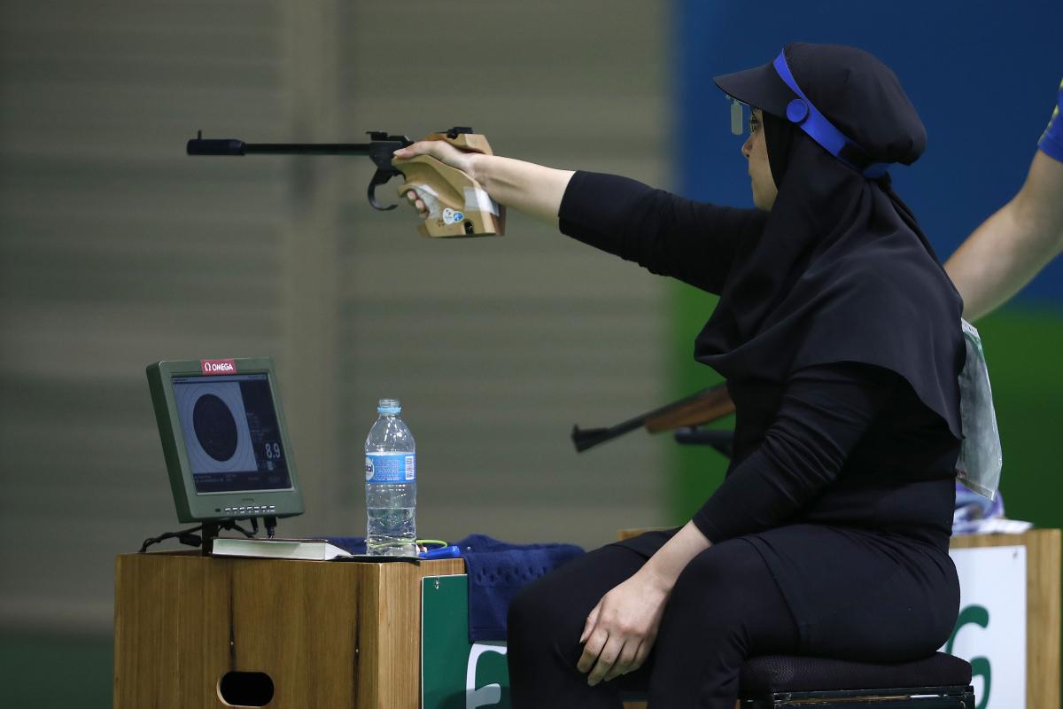 Woman with black headscarf aiming with a weapon