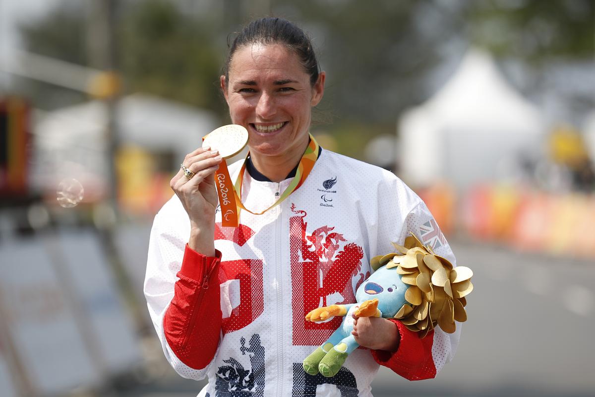 Woman in track suit showing a medal to the camera