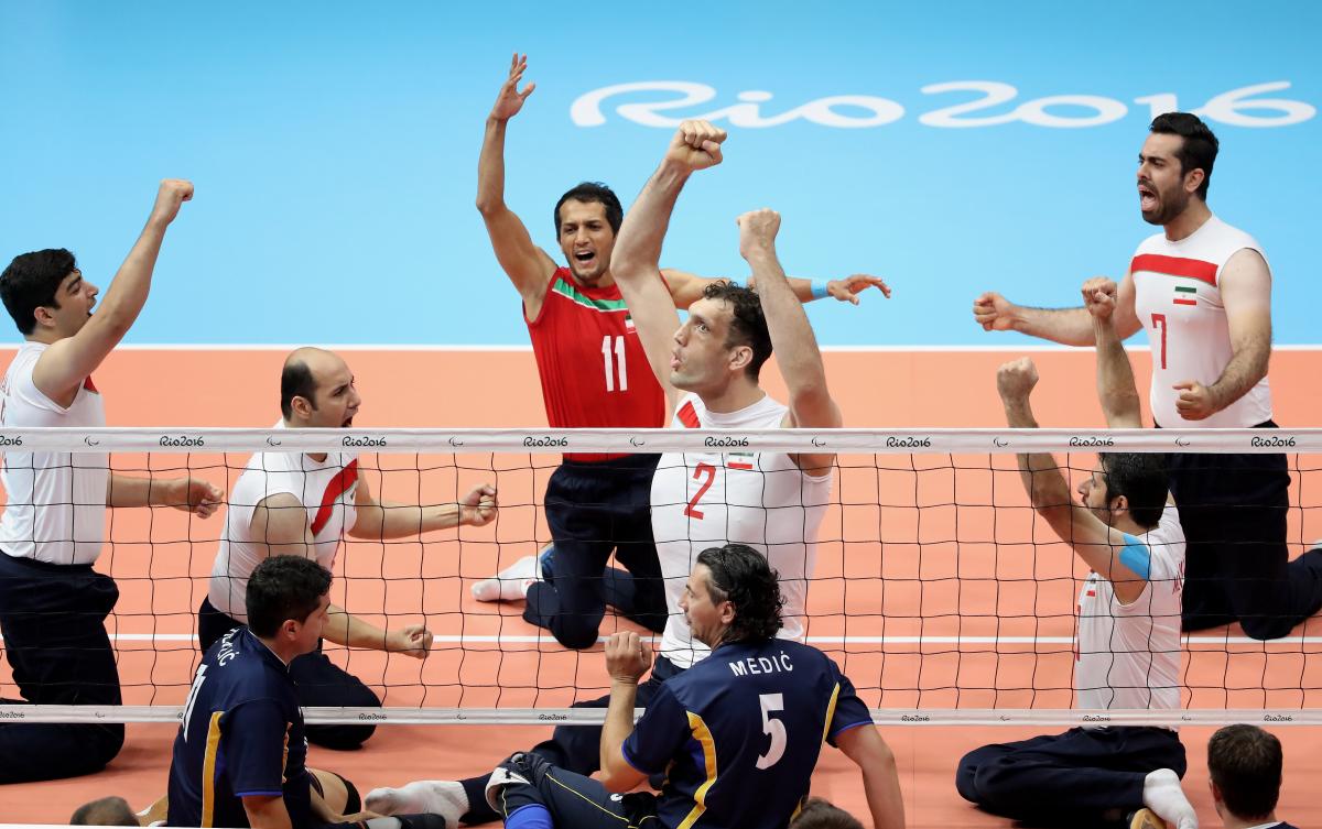 Group of sitting volleyball players celebrate after a point. 
