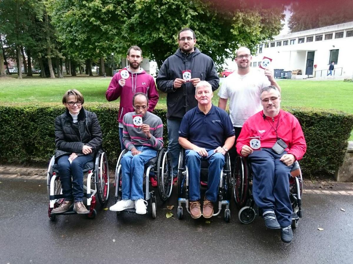 Five people in wheelchairs and standing pose with certificates