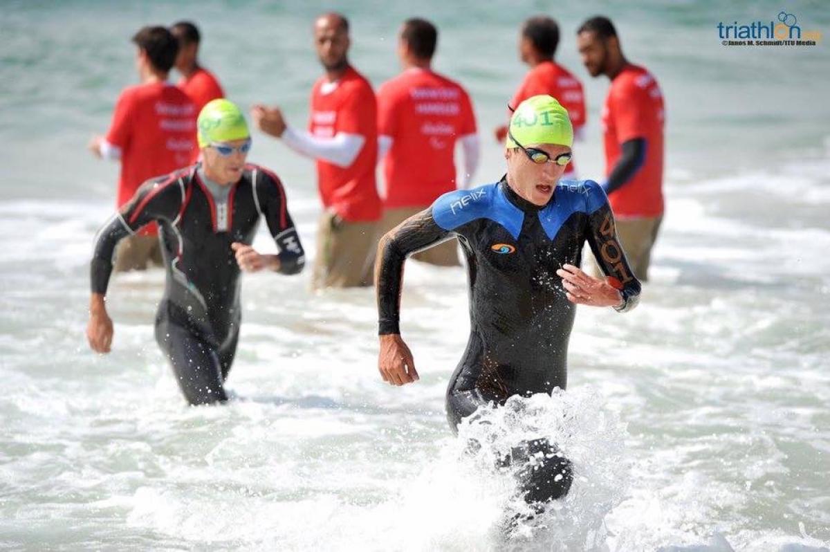 Two men in wet suits coming out of the water