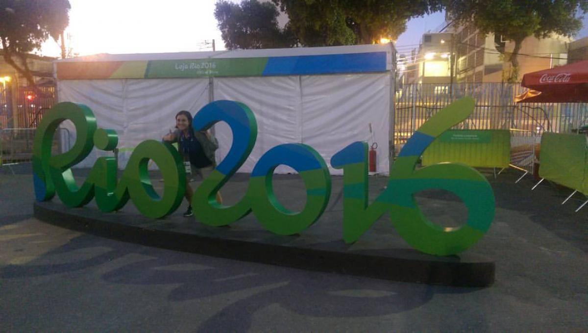 Emily Bayci - archery writer Woman posing in front of Rio 2016 sign