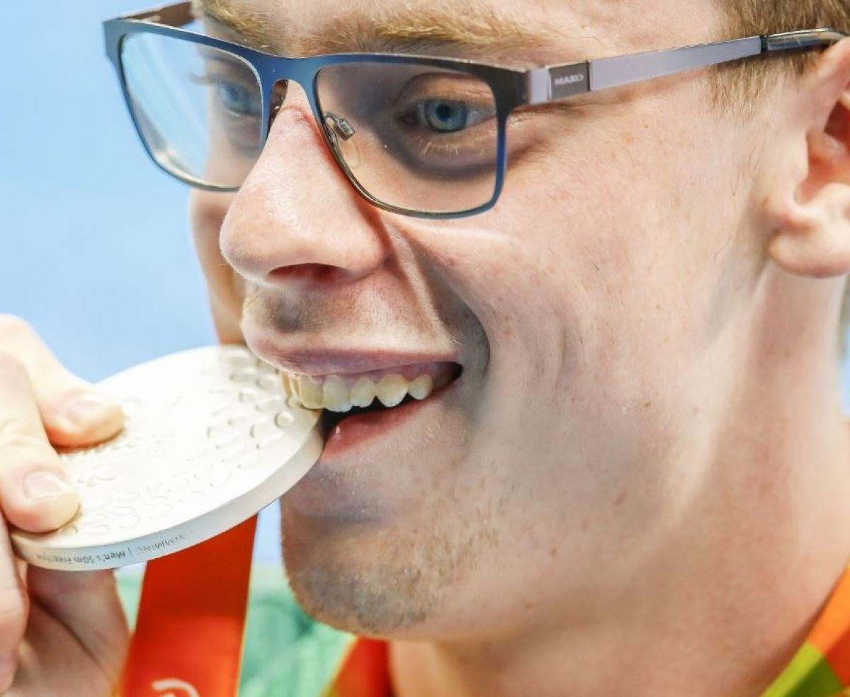 Tim Disken - Australia - swimming Face of a man biting on a medal