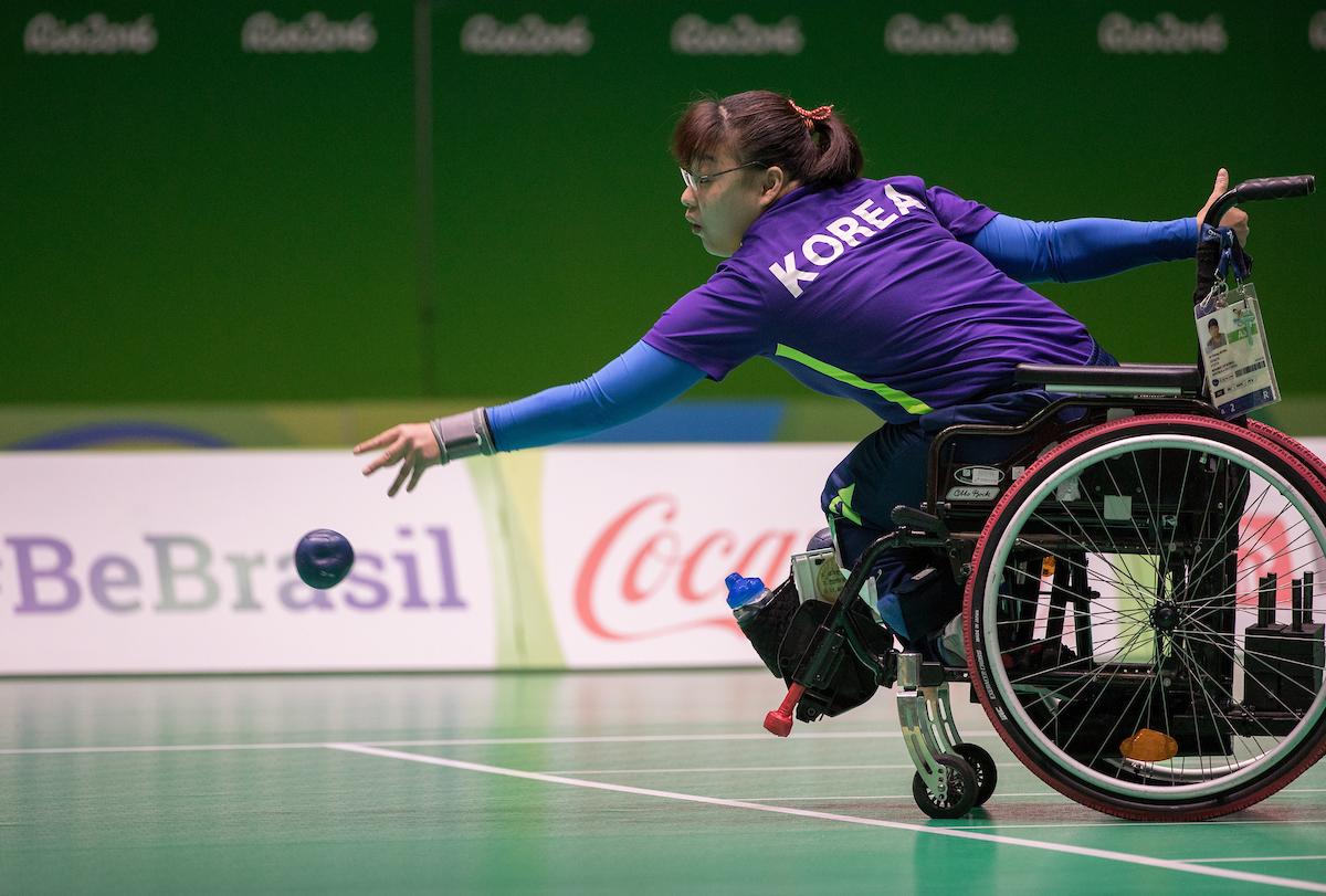 Woman in wheelchair throwing a blue boccia ball