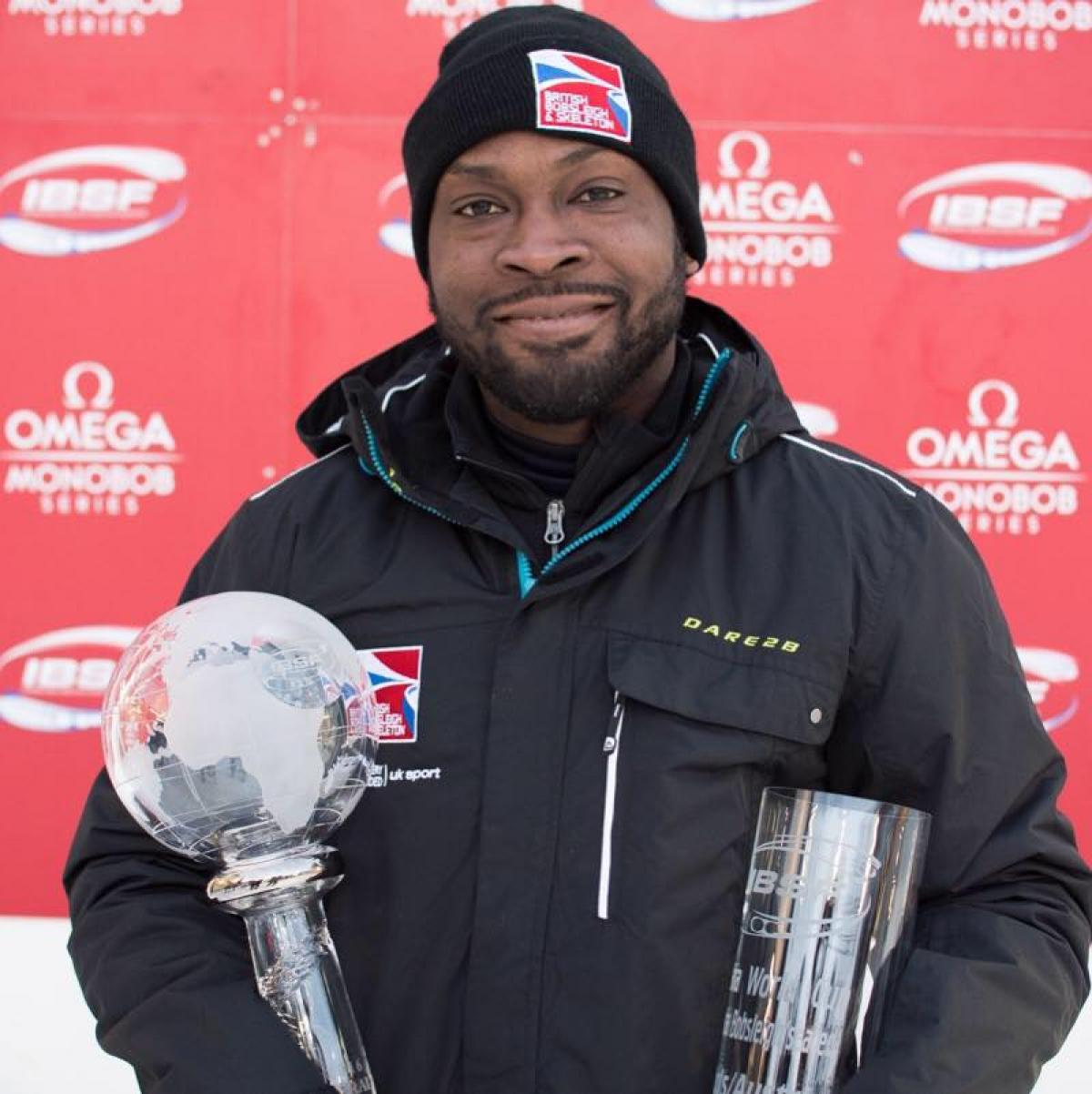 Profile picture of a man who smiles and holds a trophy in his hands