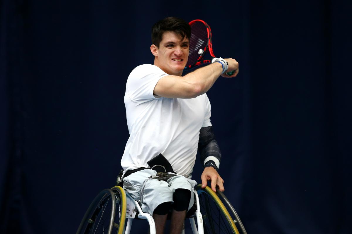 Wheelchair tennis player hits a ball.