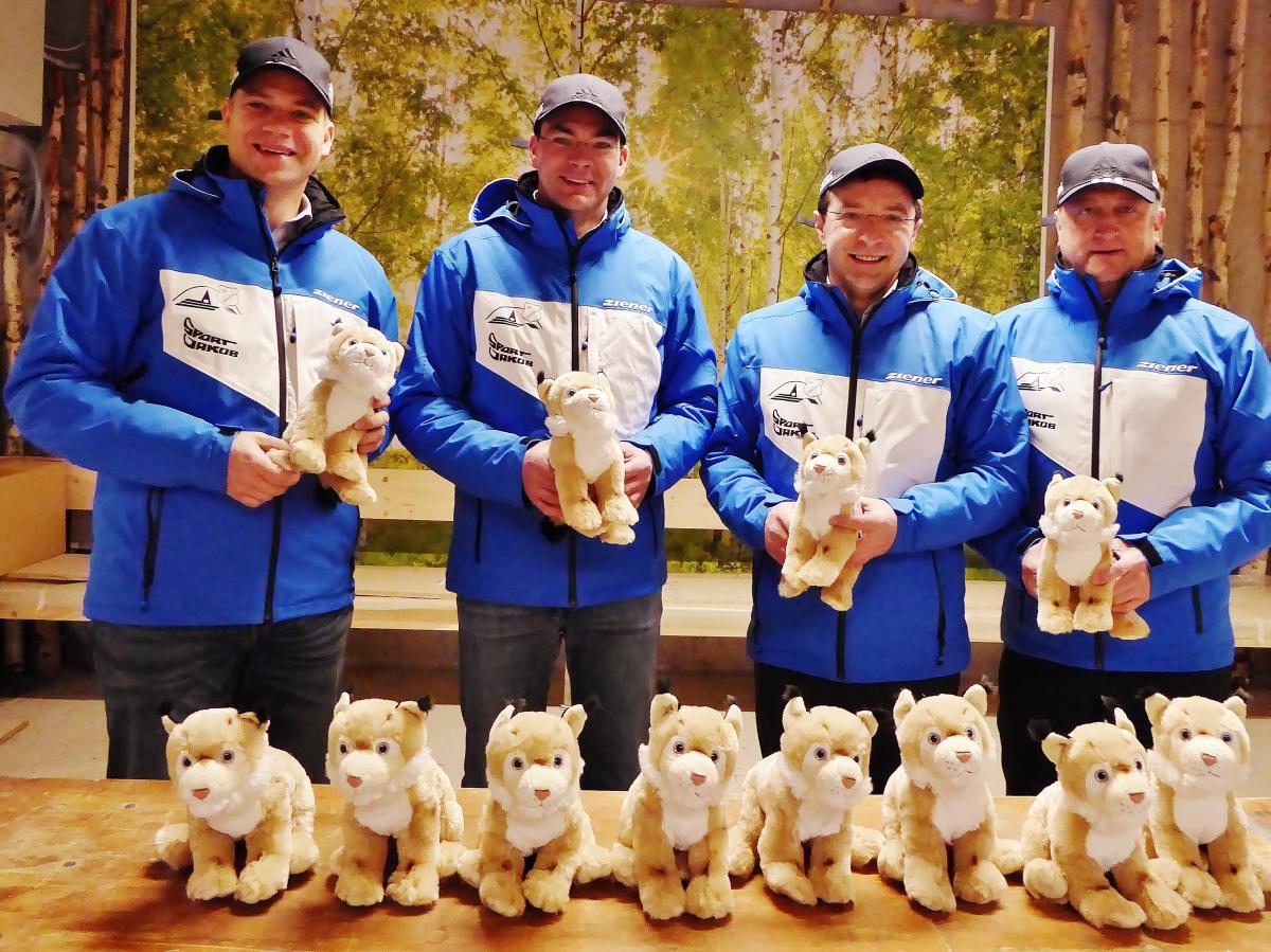 Four men in blue jackets show toys